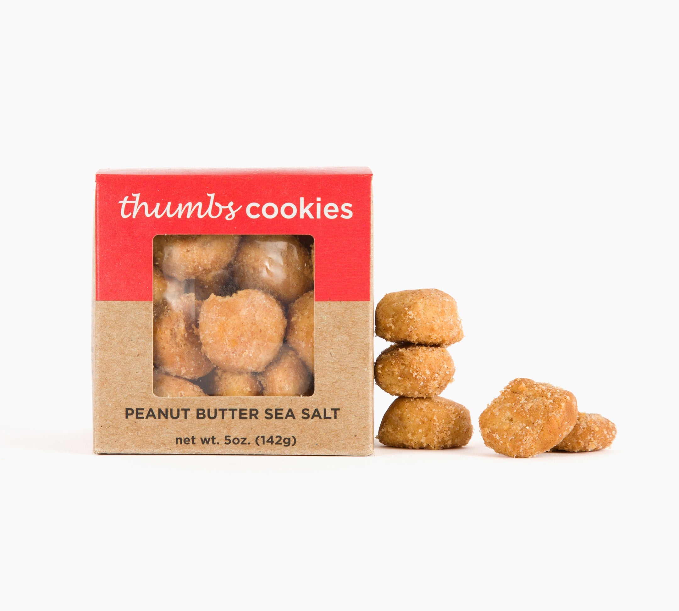 A box labeled "Thumbs Cookies" with peanut butter sea salt flavor is shown next to a small pile of golden cookies, lightly dusted with sea salt. The net weight is 5 oz (142g).